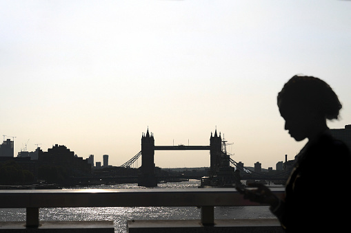 Business worker walking along London Bridge to work using a smartphone