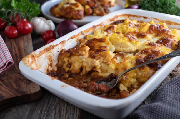 Delicious gluten free casserole dish with chili con carne and a tasty potato cheese crust. Served on wooden table background with cross section view. Ready to eat