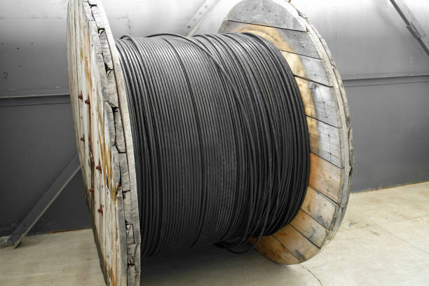 New blue power cable is wound on wooden coil. Background New black power cable is wound on wooden coil. Background. Cable for laying underground. wooden spool stock pictures, royalty-free photos & images