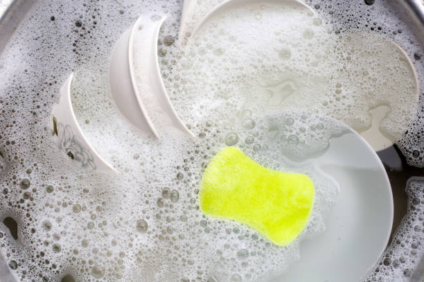 istock Washing dishes, Close up of utensils soaking in kitchen sink. 1390806487
