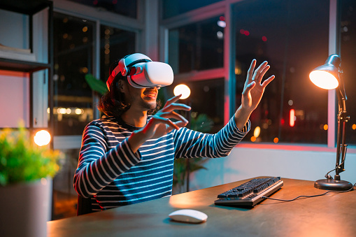 Creative Asian Young male man wearing smart virtual  glasses and joining business meeting on augmented reality metaverse working space,asia man using a VR headset to explore virtual space video conference abroad country at night