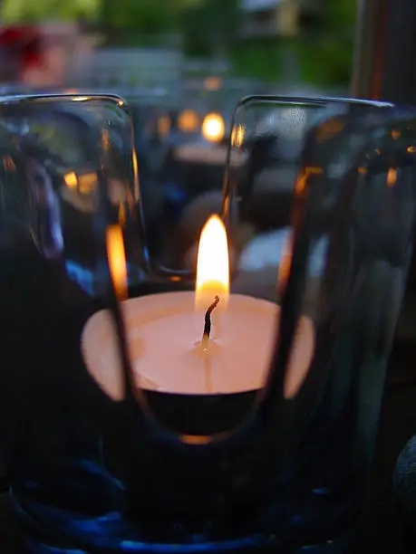 A close-up of a tealight in an elegant base in a summer's evening
