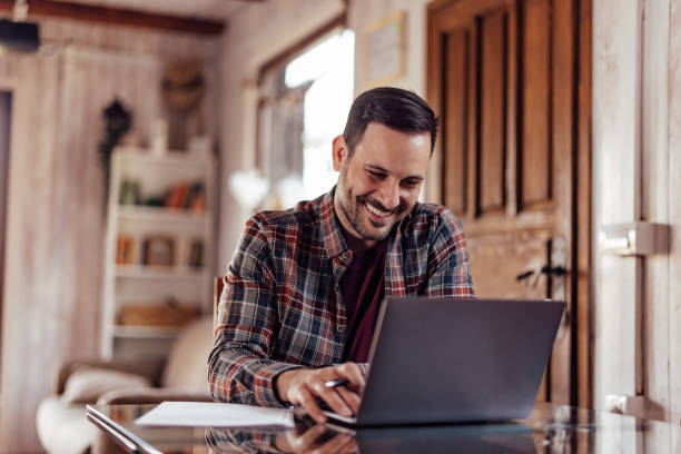 istock Smiling man working online, typing something on the laptop keyboard. 1390809298