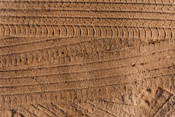Photo of Car wheel tracks on dry sand