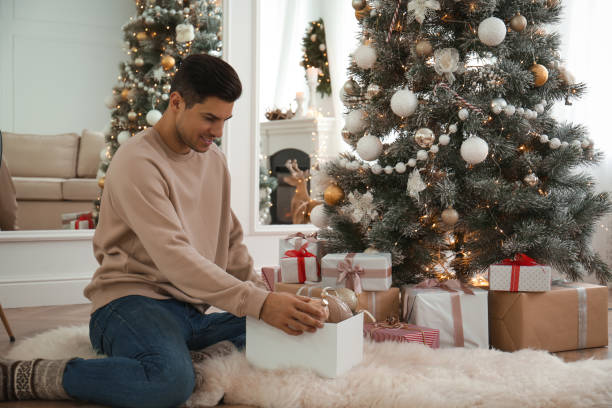 istock Man decorating Christmas tree in beautiful room interior 1390810557