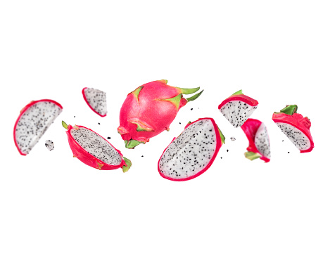 Whole and chopped red dragon fruits (pitahaya) in the air on a white background