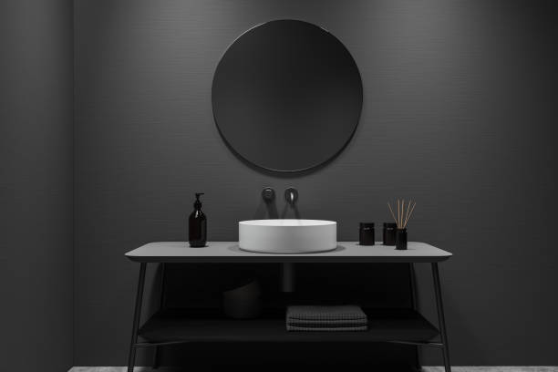 istock Front view on dark bathroom interior with round mirror, sink 1390811375