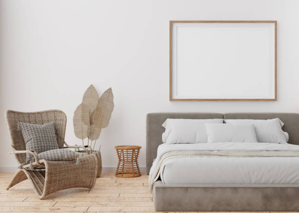 istock Empty picture frame on white wall in modern bedroom. Mock up interior in boho style. Free, copy space for your picture, poster. Bed, rattan armchair, parquet floor. 3D rendering. 1390811724