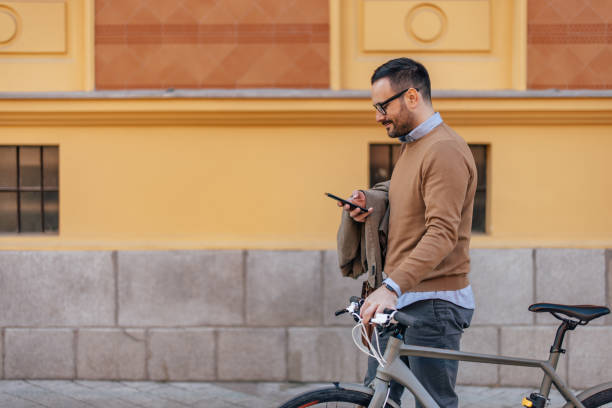 istock Side shot, caucasian man focused on his mobile, holding his bicycle. 1390812949