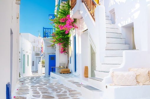 The island of Mykonos, Greece. Streets and traditional architecture. White-colored buildings and bright flowers. Travel photography.