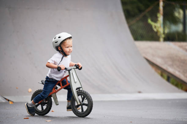 istock Toddler kid learning to ride on run bicycle at skate park. 1390815639