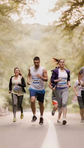 Group of athletes running a marathon through nature. Copy space.