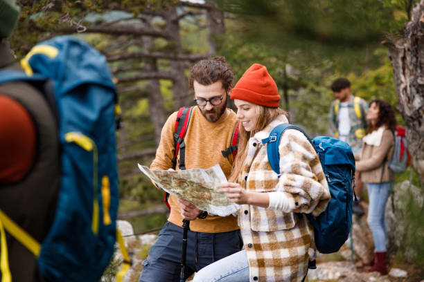 jeune couple de randonneurs lisant une carte dans la forêt. - orienteering photos et images de collection