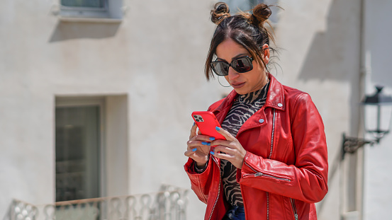 Young woman influencer in red jacket viewing her likes before a photo shoot