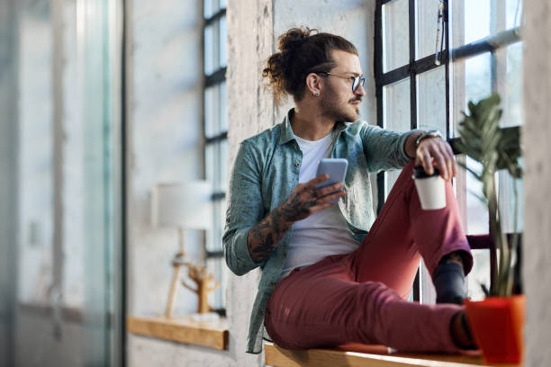 istock Male freelancer using cell phone on coffee break by the window. 1390817971