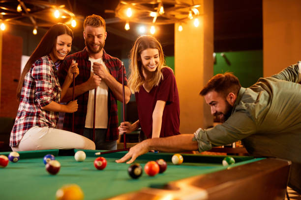 istock Group of friends having fun while playing pool in a local pool hall 1390818143