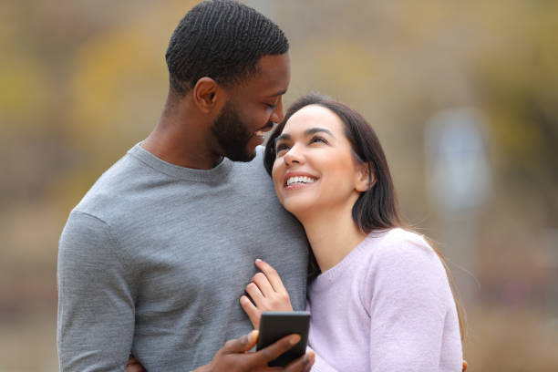 Happy couple holding phone looking each other in love stock photo