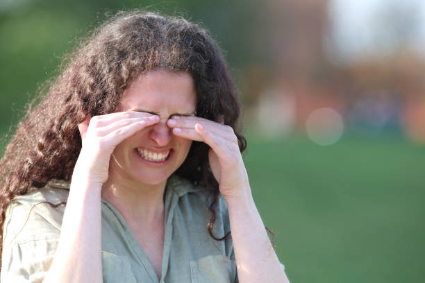 mujer estresada rascándose los ojos con picazón en un parque - frotarse los ojos fotografías e imágenes de stock