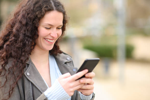 istock Happy woman checking cell phone walking in a park 1390819598