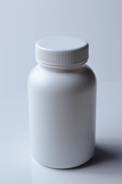 istock white plastic medicine jar and two white pills. light background. 1390819749