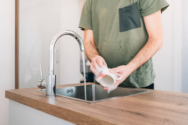 istock Man washing coffee cup at kitchen sink 1390823236