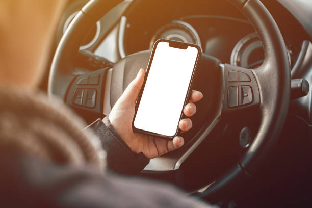 Mockup smartphone blank white screen in female driver hand over steering wheel stock photo