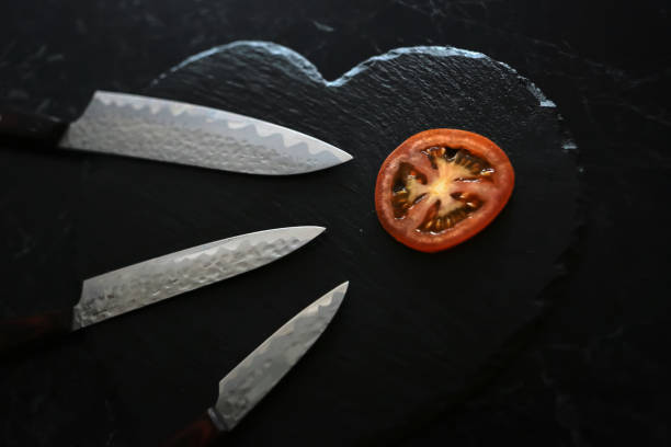 Knives and tomato Knives cutting tomato on the wooden board with black background knif stock pictures, royalty-free photos & images