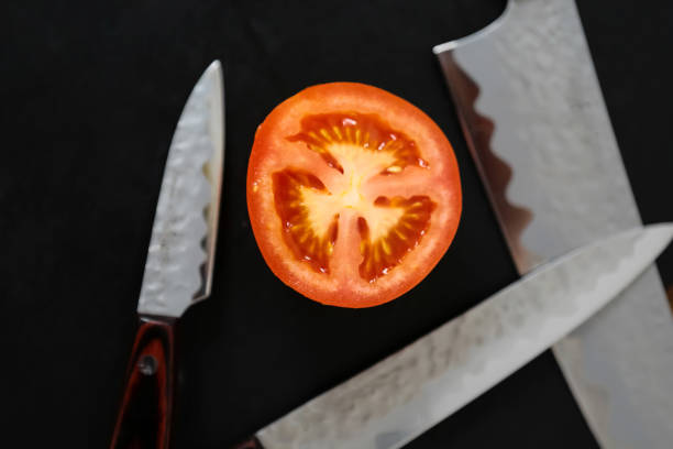 Knives and tomato Knives and cutted tomato on the black board knif stock pictures, royalty-free photos & images