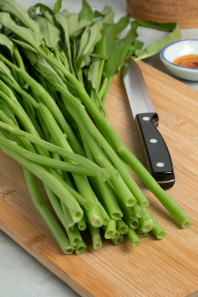 istock Fresh water spinach on a wooden cutting board close up 1390826442