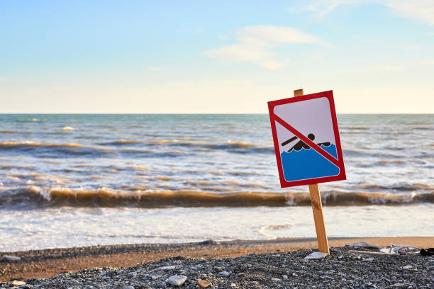 avertissement pas de panneau de baignade avec une forte vague de mer par le fond de la plage - sea water surf tide photos et images de collection