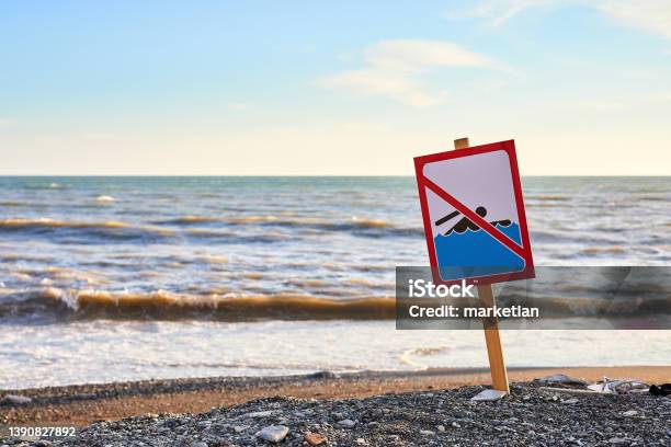 Warning No Swimming Sign With Strong Sea Wave By The Beach Background Stock Photo - Download Image Now