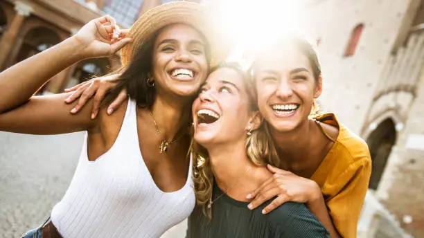 Photo of Three young multiracial women having fun on city street outdoors - Mixed race female friends enjoying a holiday day out together - Happy lifestyle, youth and young females concept