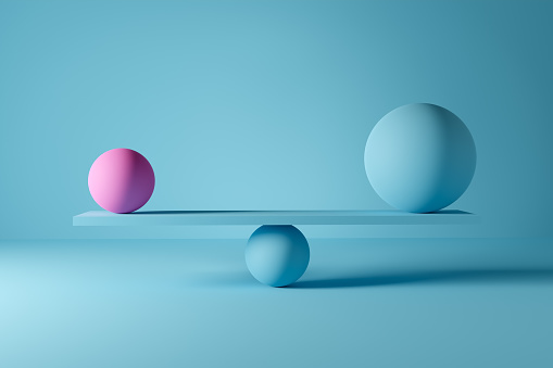 Big blue ball and small pink ball balancing on a scale. Power balance or harmony concept.