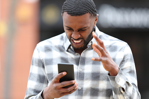 Angry man with black skin checking phone problem