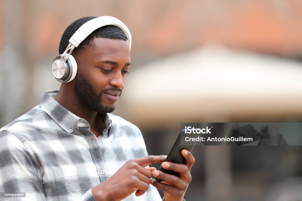 Man with black skin listening to music walks in the street Listening Stock Photo