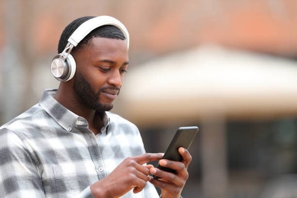 Man with black skin listening to music walks in the street stock photo
