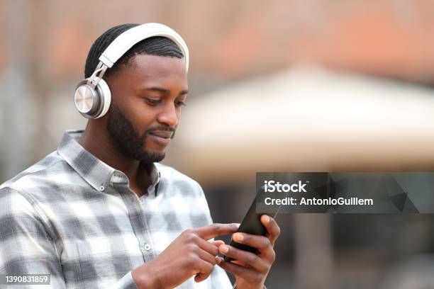 Man With Black Skin Listening To Music Walks In The Street Stock Photo - Download Image Now