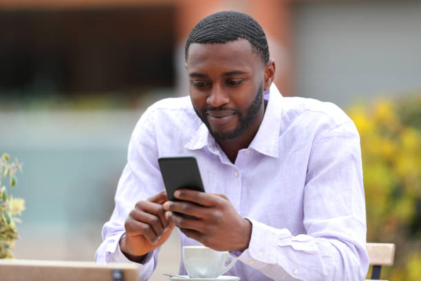 istock Man with black skin using smart phone in a bar 1390832005