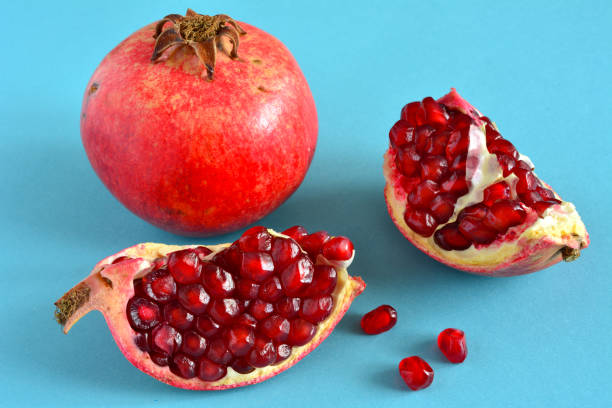 istock pomegranate fruit with seeds on blue background, close-up 1390832295