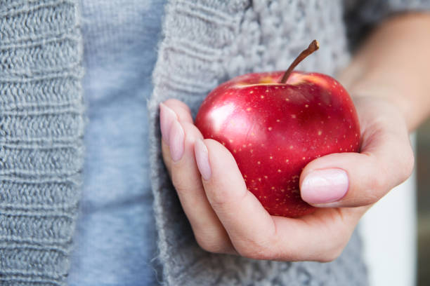 istock Red mature juicy apple in female hands. 1390832549