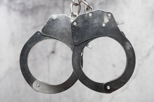 istock pair of handcuffs in front of a cement wall 1390834665