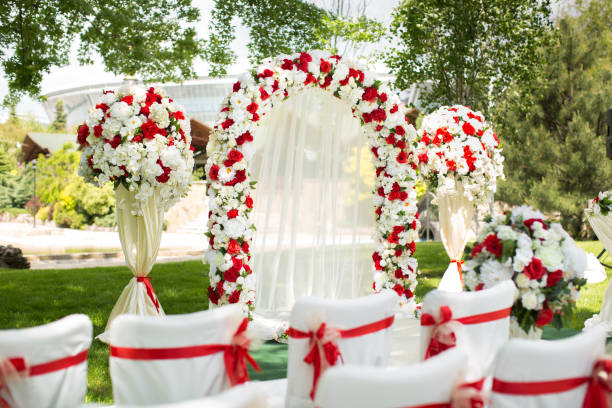 istock Wedding ceremony outdoors. Wedding arch decorated with red flowers 1390834725