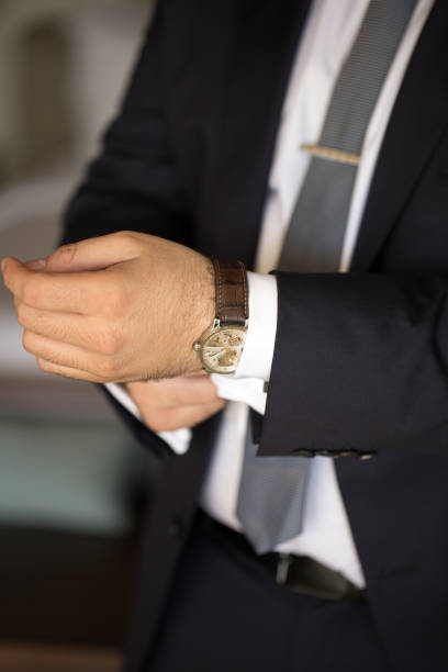 istock A man in a suit puts a watch on his hand. 1390836069