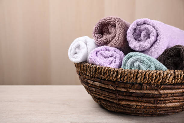 istock Rolled soft towels in wicker basket on wooden table. Space for text 1390836088