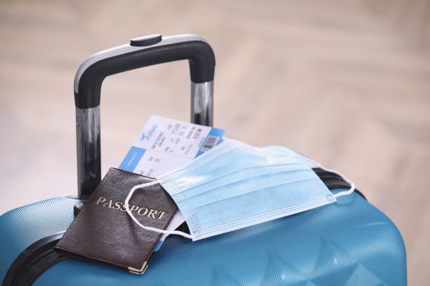 istock Passport, protective mask and tickets on blue suitcase. Travel during quarantine 1390836156