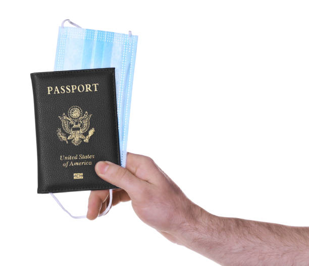 istock Man holding passport and protective mask on white background, closeup. Travel during quarantine 1390836238