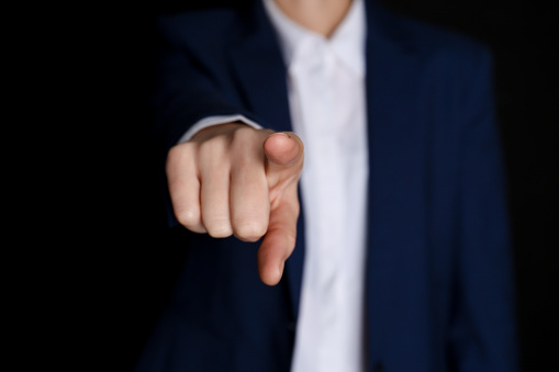 Businesswoman pointing at something on black background, closeup. Finger gesture
