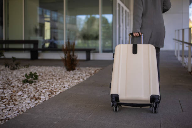 istock Rear-view of unrecognizable woman pulling her suitcase, while arriving at the airport 1390842143