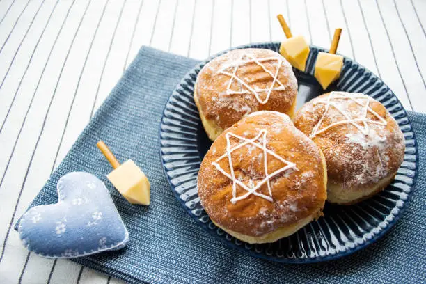 Happy Hanukkah banner. A traditional treat of doughnuts with David star and dreidel made from cheese and biscuit sticks.