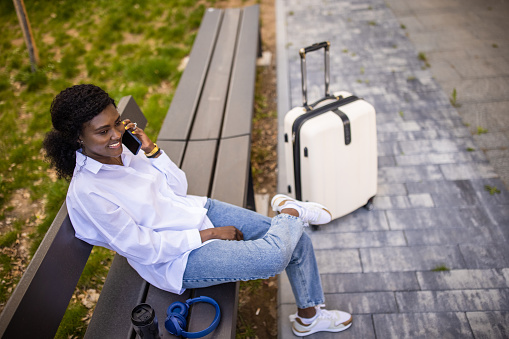 Young woman Black ethnicity talking on mobile phone, while waiting for her transportation